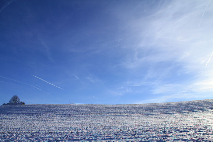 blauer Himmel über Schneefeld